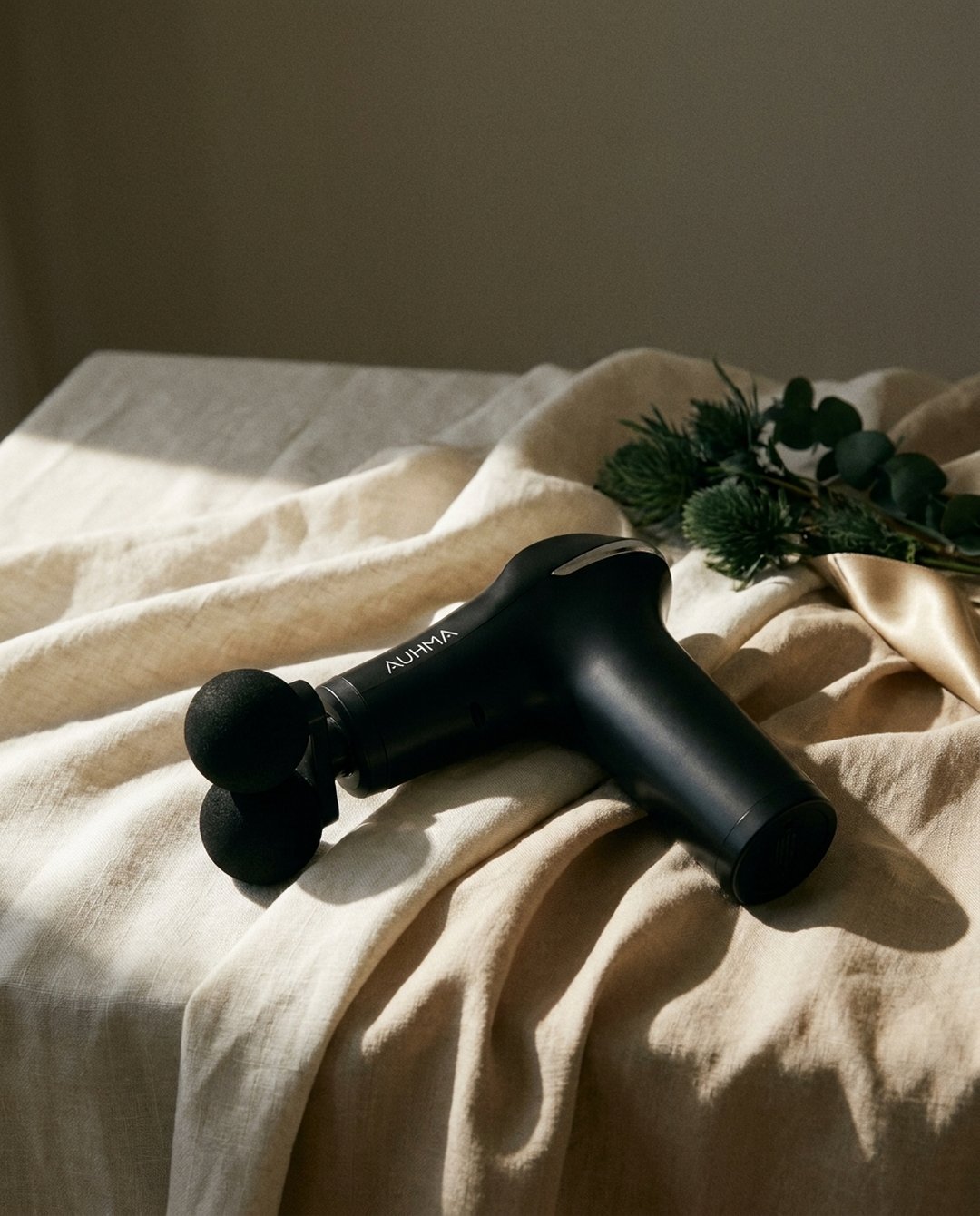 Auhma Massage Gun — packshot éditorial sur lin naturel